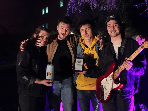 The four members of Daytrails posing outside for a photo. One is holding a guitar