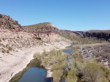 Drone image of a valley in the desert with a river and greenery. A bridge can be seen in the distance. Image by Nathan Hadland.