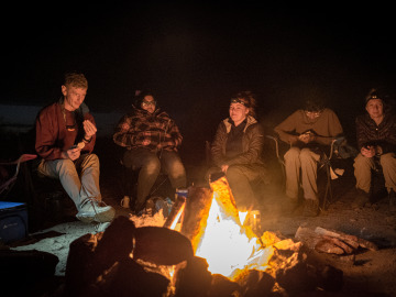 Students and Professor Byrne sit around a camp fire in the desert. Image by Harry Tang