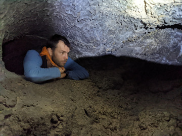 A student climbs through a tight spot in the lava tube. Image by Robert Melikyan