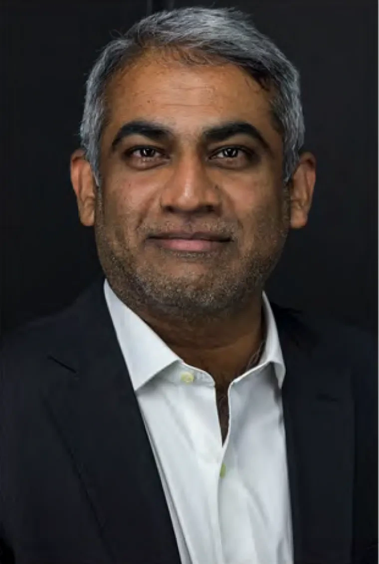 Professor Reddy smiling at camera against a dark background