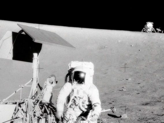 NASA astronaut Pete Conrad standing next to Surveyor 3 with the Apollo 12 Lunar Module Intrepid in the background. (NASA photo by Alan Bean)