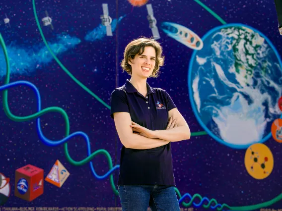 Photo of Carina Bennett in front of OSIRIS-REx mural