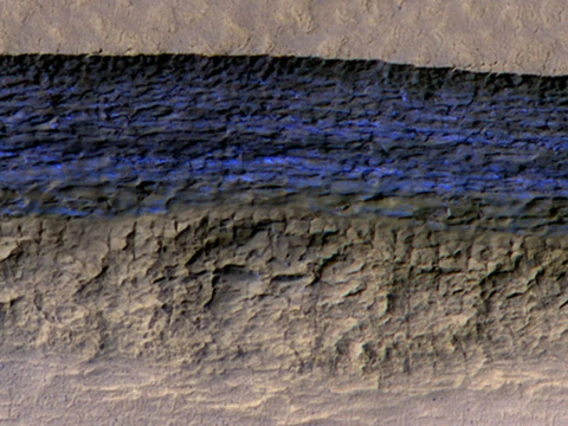 At this pit on Mars, the steep slope at the northern edge (toward the top of the image) exposes a cross section of a thick sheet of underground water ice. The image is from the HiRISE camera on NASA's Mars Reconnaissance Orbiter, with an enhanced-color central swath between grayscale on each side. (Image: NASA/JPL-Caltech/UA/USGS)