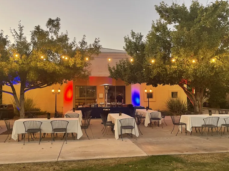 Tables setup under trees with string lights for a banquet!