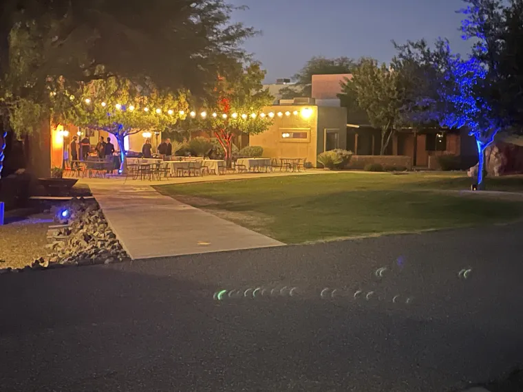 People at outside banquet tables with colorful lights and outdoor space heaters